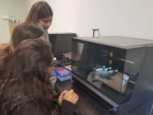 Students watching the Carvey CNC machine carving a tile.