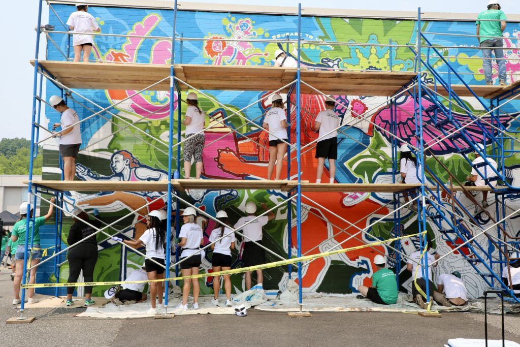 students painting mural on school